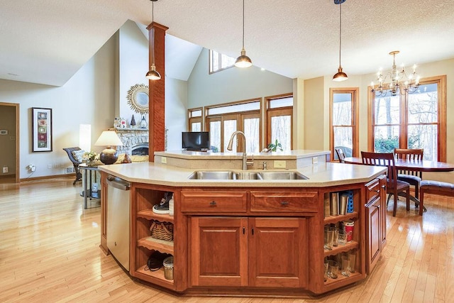 kitchen with sink, decorative light fixtures, a kitchen island with sink, and dishwasher