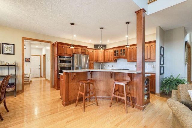 kitchen with appliances with stainless steel finishes, sink, a breakfast bar area, and light hardwood / wood-style flooring