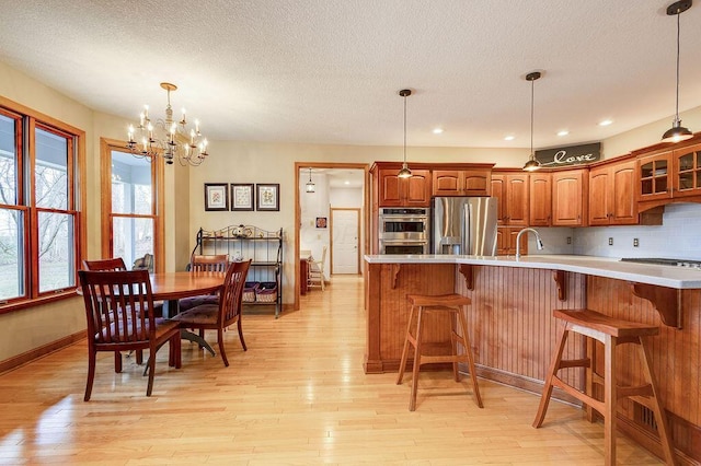 kitchen featuring tasteful backsplash, sink, a breakfast bar area, stainless steel appliances, and light wood-type flooring