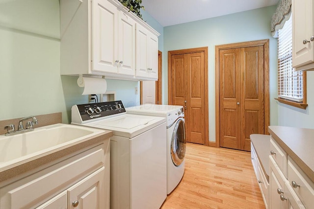 laundry room featuring cabinets, washing machine and dryer, sink, and light wood-type flooring