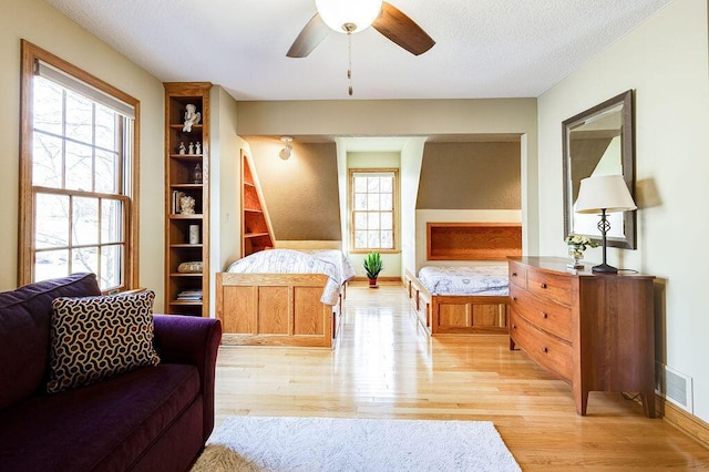 bedroom with a textured ceiling, multiple windows, and light hardwood / wood-style flooring