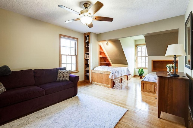 bedroom with ceiling fan, light hardwood / wood-style flooring, and a textured ceiling