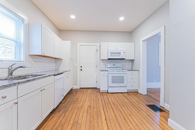 kitchen featuring white cabinetry, sink, light hardwood / wood-style floors, light stone countertops, and white appliances