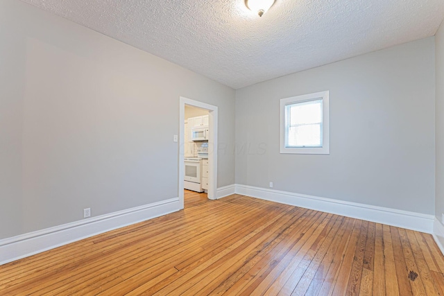 spare room featuring light hardwood / wood-style flooring and a textured ceiling