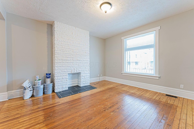 unfurnished living room with a textured ceiling, a fireplace, and wood-type flooring