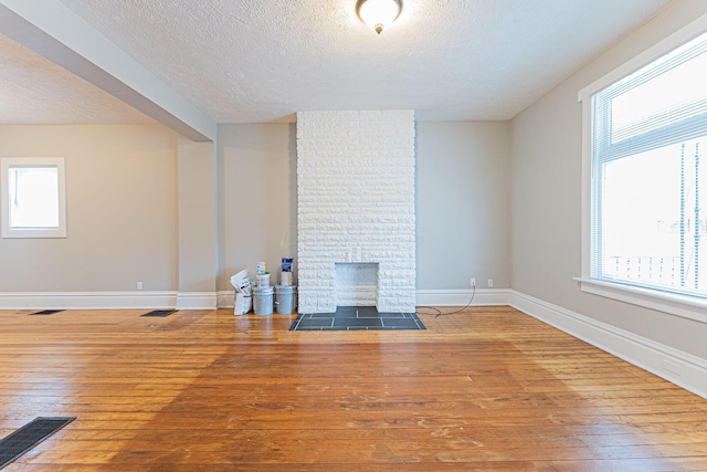 unfurnished living room featuring hardwood / wood-style flooring, a fireplace, and a textured ceiling