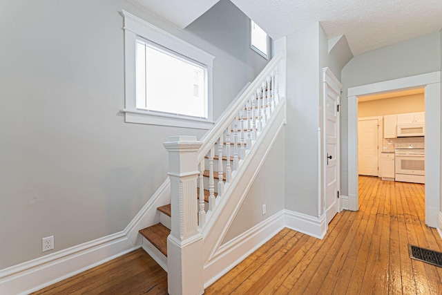 stairs featuring hardwood / wood-style floors and a textured ceiling