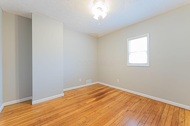 unfurnished room featuring a textured ceiling and light wood-type flooring