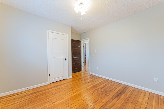 unfurnished room featuring a textured ceiling and light wood-type flooring