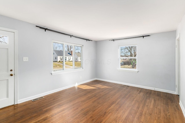 spare room with visible vents, dark wood-type flooring, and baseboards