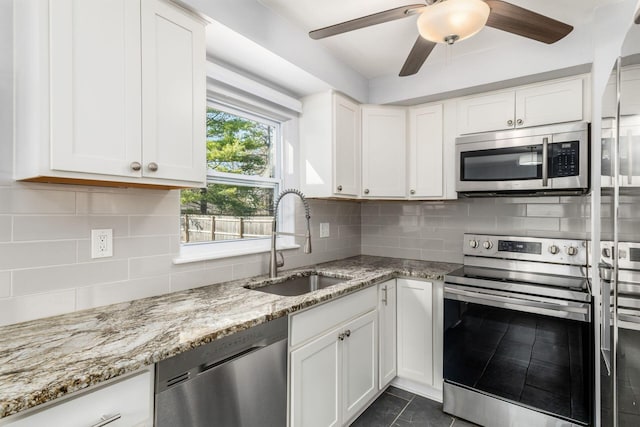 kitchen featuring a ceiling fan, a sink, tasteful backsplash, stainless steel appliances, and light stone countertops