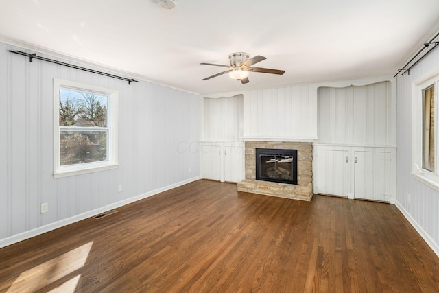 unfurnished living room with ceiling fan, visible vents, wood finished floors, and a fireplace