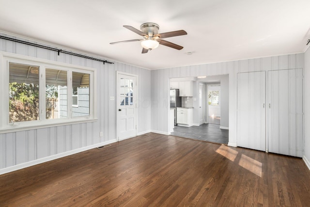 unfurnished living room featuring dark wood finished floors, a ceiling fan, visible vents, and baseboards