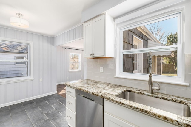 kitchen with light stone countertops, white cabinetry, a sink, dishwasher, and backsplash