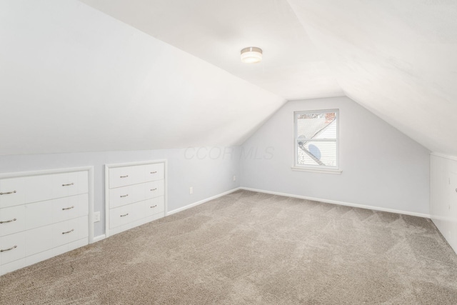 additional living space featuring baseboards, lofted ceiling, and carpet flooring