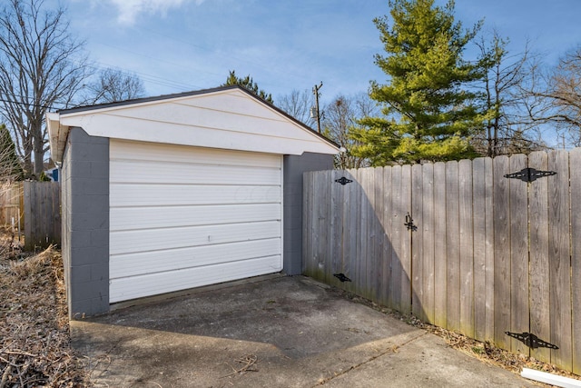 detached garage featuring a gate, driveway, and fence