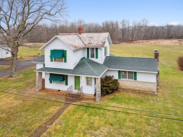 traditional home with stone siding, fence, a front yard, a shingled roof, and a chimney