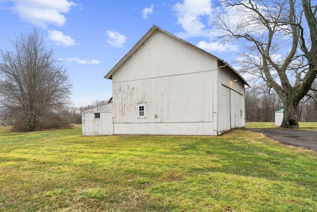 view of side of home with an outdoor structure, a yard, and a barn