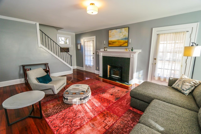 living room with hardwood / wood-style flooring, crown molding, and a tile fireplace