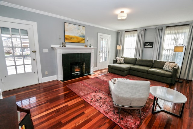 living room featuring hardwood / wood-style floors, crown molding, and a tile fireplace