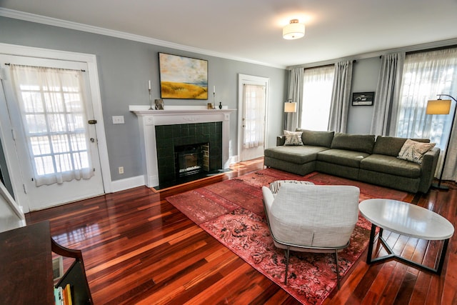 living room featuring crown molding, wood-type flooring, and a tile fireplace