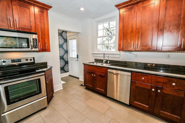 kitchen with light tile patterned flooring, appliances with stainless steel finishes, sink, dark stone countertops, and crown molding