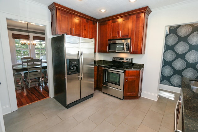 kitchen with a chandelier, light tile patterned floors, dark stone countertops, ornamental molding, and appliances with stainless steel finishes