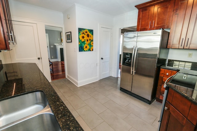 kitchen featuring dark stone countertops, crown molding, stainless steel appliances, and light tile patterned flooring