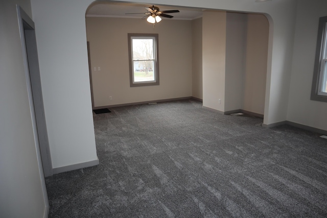 spare room featuring crown molding, ceiling fan, and dark colored carpet