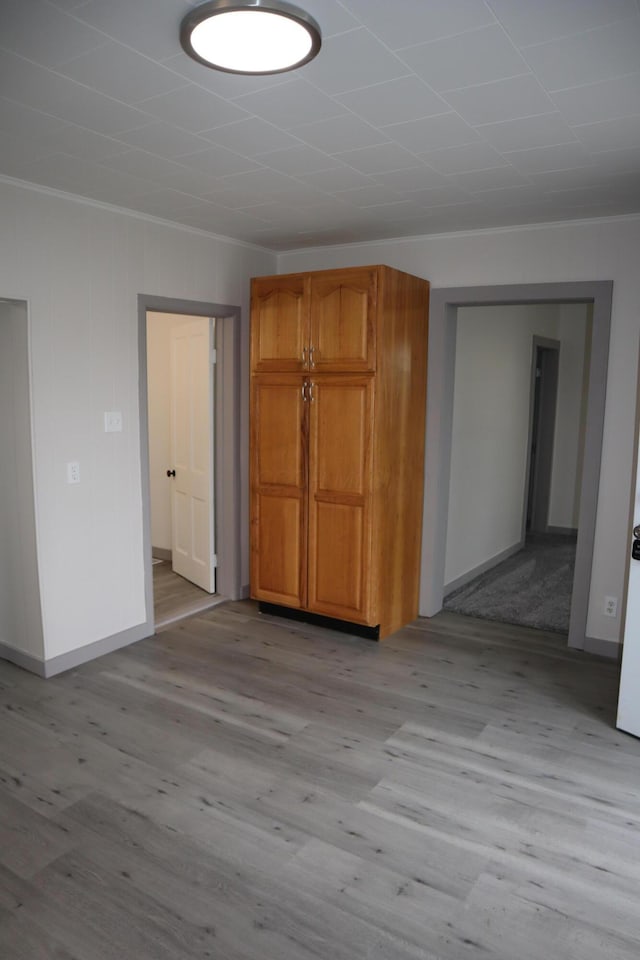 spare room featuring crown molding and light hardwood / wood-style floors