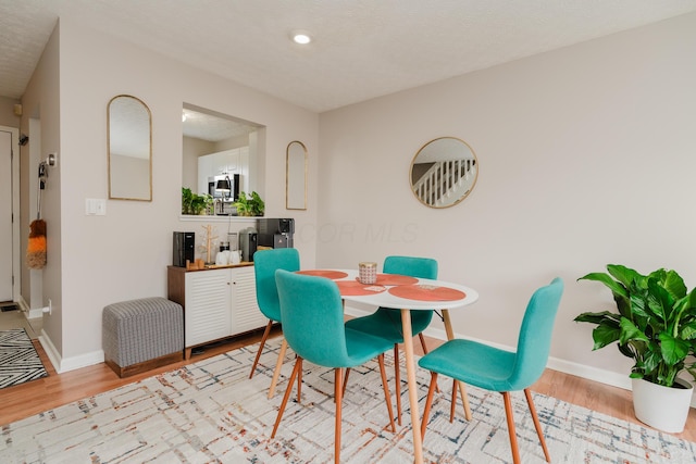 dining room featuring a textured ceiling and light wood-type flooring