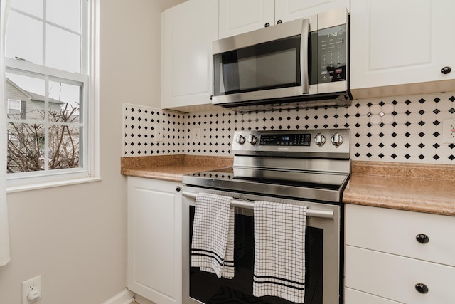 kitchen with stainless steel appliances, tasteful backsplash, and white cabinets