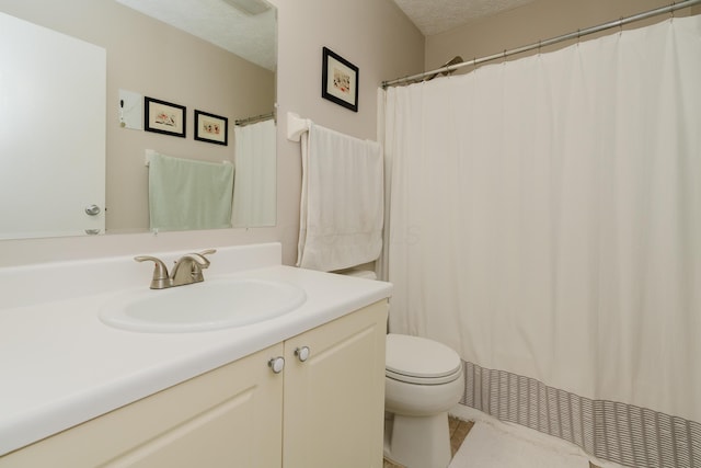 bathroom featuring vanity, a textured ceiling, and toilet