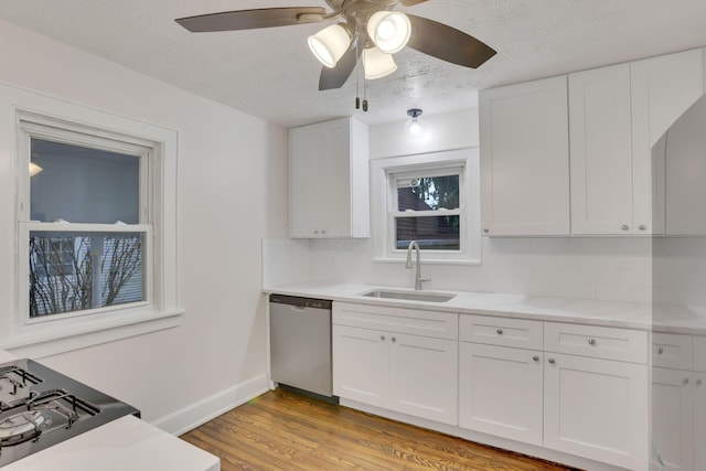 kitchen with sink, white cabinetry, light hardwood / wood-style flooring, stainless steel dishwasher, and backsplash