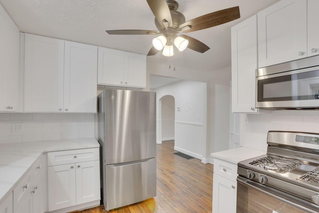 kitchen featuring white cabinetry, stainless steel appliances, light stone countertops, and light hardwood / wood-style flooring