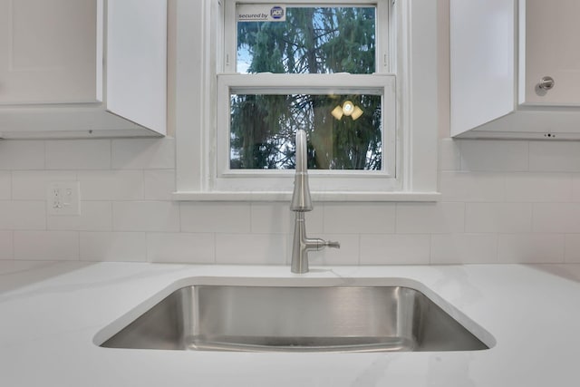 room details featuring sink, backsplash, and white cabinets