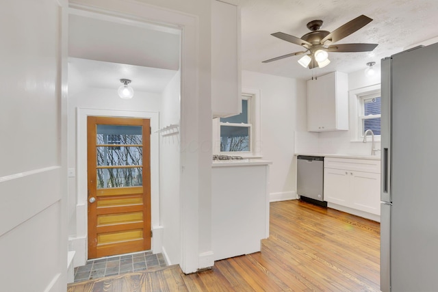 kitchen with sink, ceiling fan, white cabinetry, stainless steel appliances, and light wood-type flooring