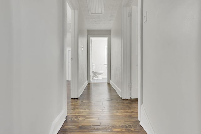 hall with dark wood-type flooring and a textured ceiling