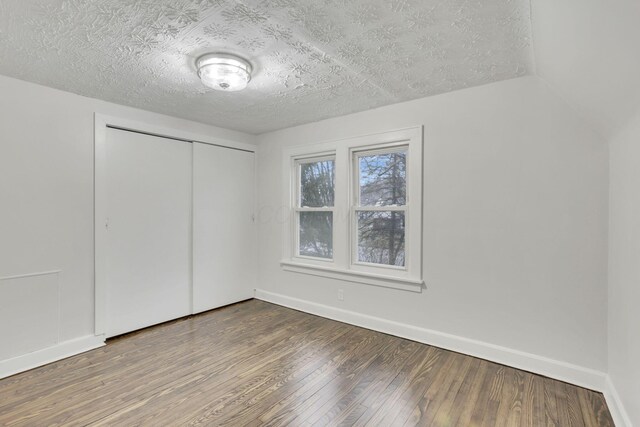 unfurnished bedroom with wood-type flooring, a closet, and a textured ceiling