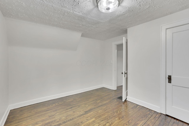 spare room with dark wood-type flooring and a textured ceiling