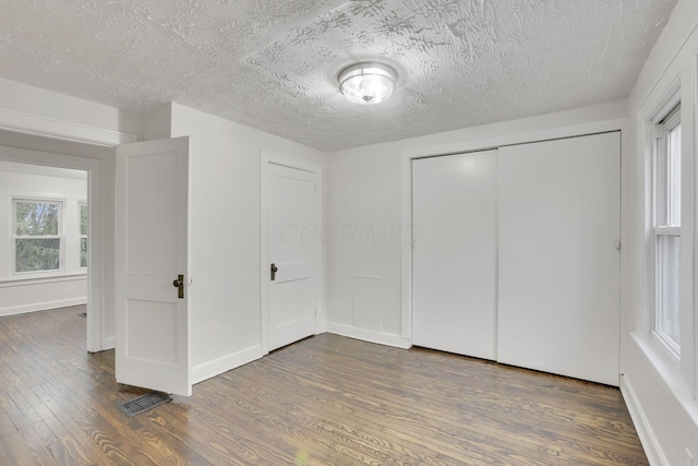 unfurnished bedroom featuring dark hardwood / wood-style flooring, a closet, and a textured ceiling