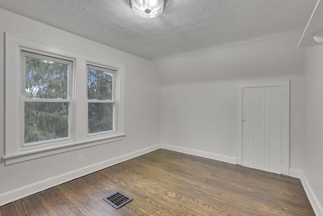 additional living space featuring lofted ceiling, a textured ceiling, and dark hardwood / wood-style flooring