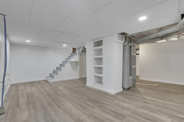 basement with a paneled ceiling and light wood-type flooring