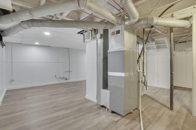 basement with heating unit and light hardwood / wood-style flooring