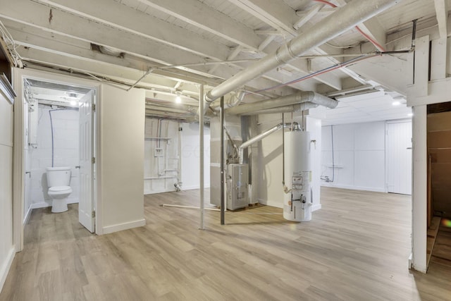 basement featuring light hardwood / wood-style flooring, heating unit, and gas water heater