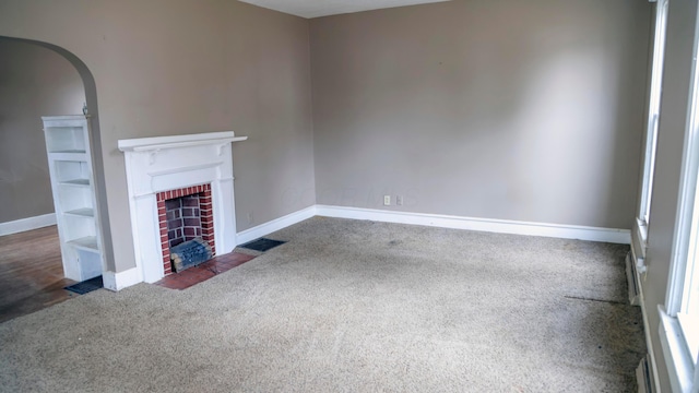 unfurnished living room featuring dark carpet and a fireplace