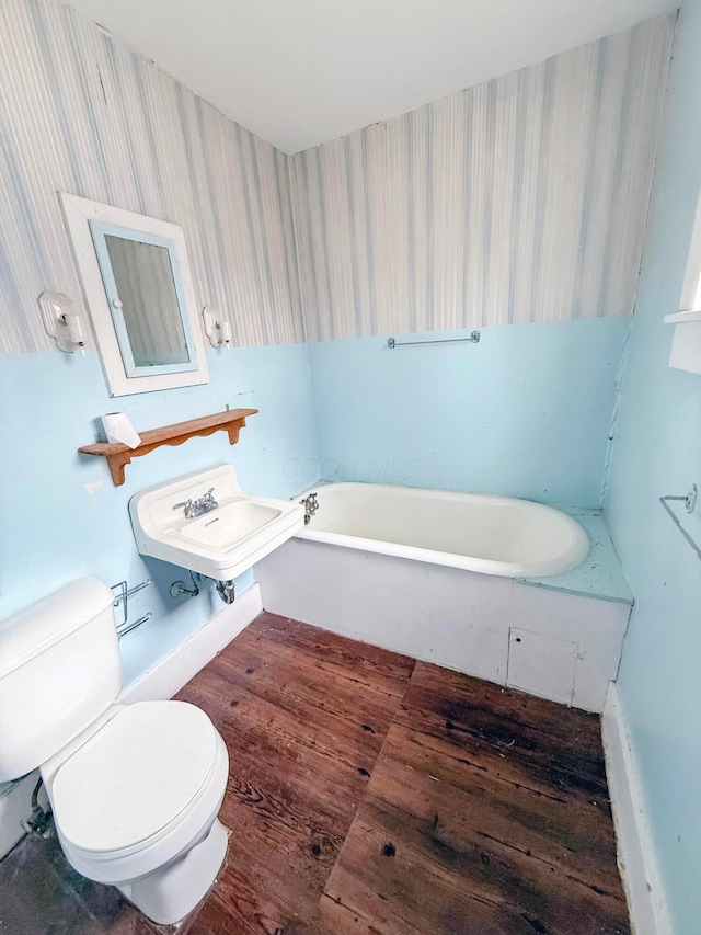 bathroom featuring toilet, a bathing tub, and sink