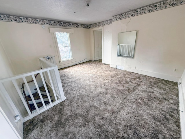 carpeted empty room with a textured ceiling