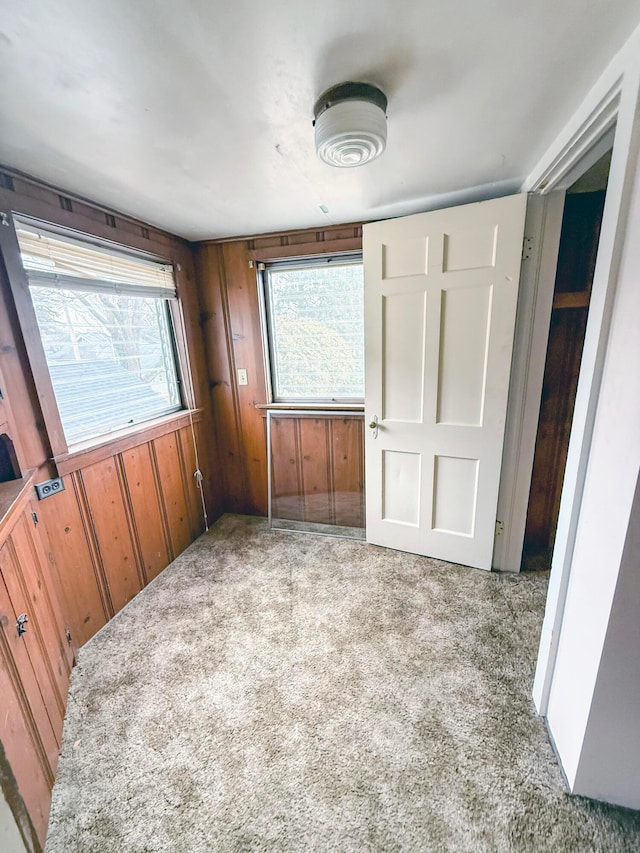 unfurnished bedroom featuring carpet floors and wooden walls