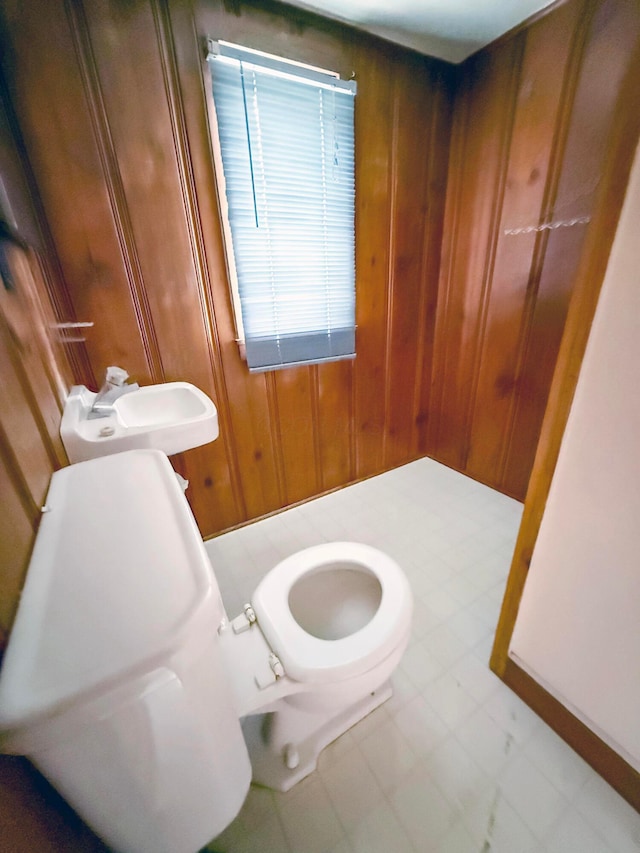 bathroom featuring toilet and wood walls